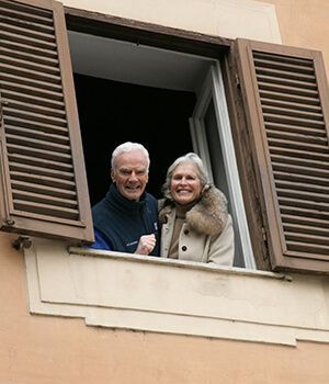 A man and a woman are looking out of a window.