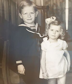 A black and white photo of a boy and a girl standing next to each other.