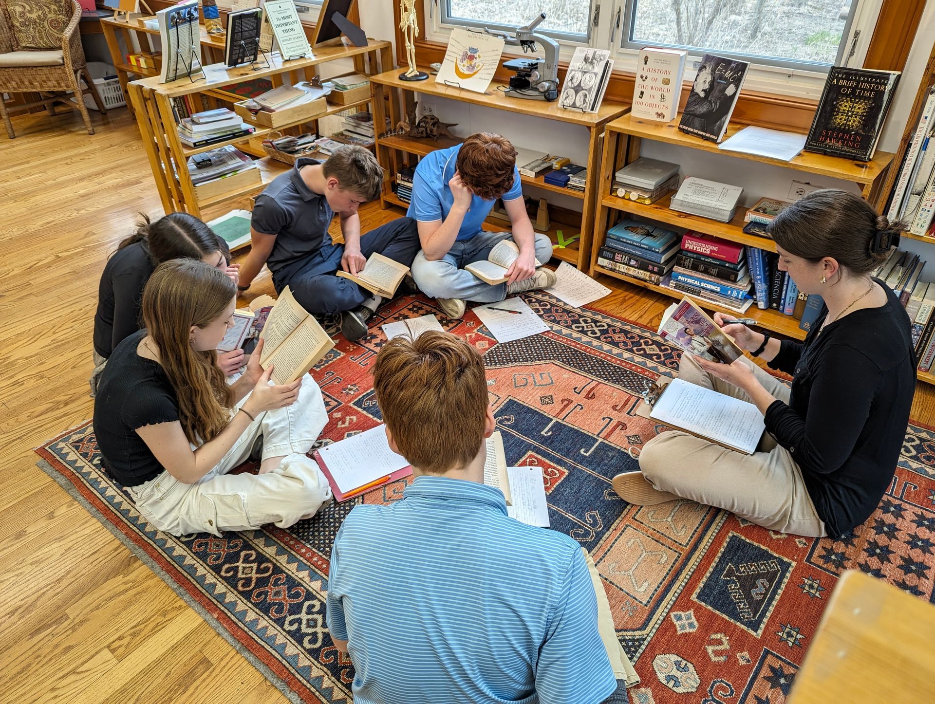 A group of Montessori children are sitting on the floor reading books.