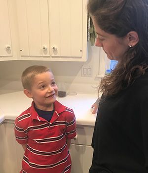 A woman is talking to a young boy in a kitchen.