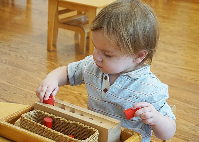 A young boy is playing with a wooden toy.