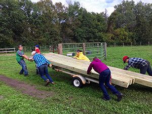 A group of people are pushing a trailer full of wooden boards.