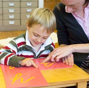 A boy is following the letters wih his fingers Montessori style