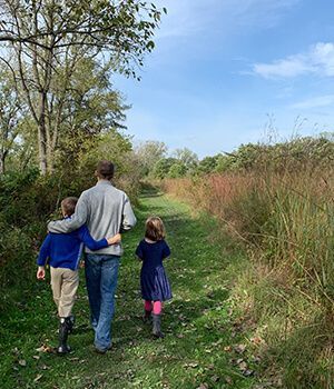 A man and two children are walking down a path.