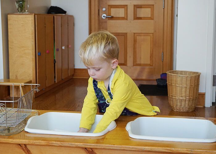 A young boy is washing in a white sink 