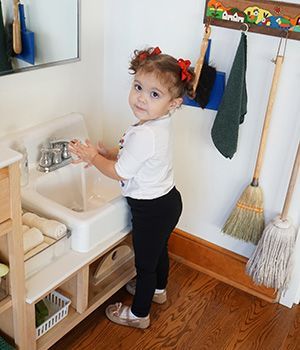 A little girl is washing her hands in a bathroom sink