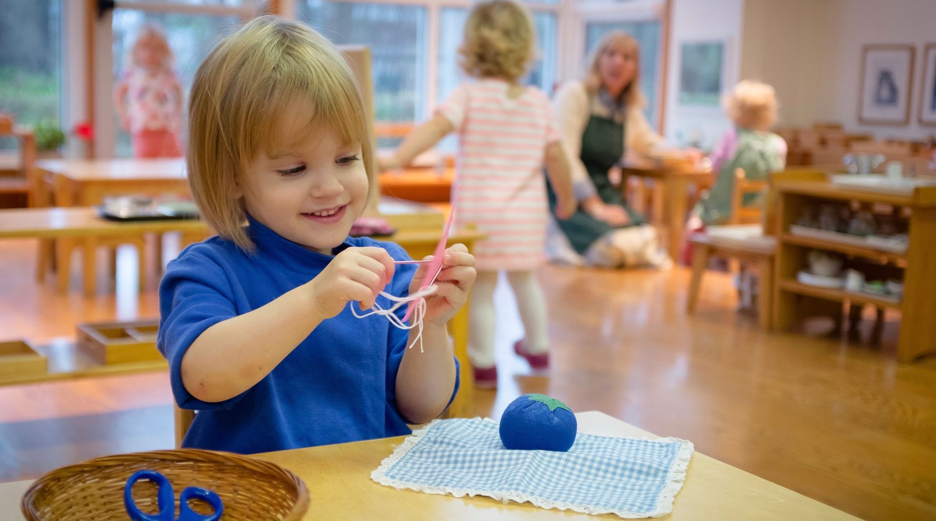 A Montessori child is sitting at a table in a classroom working with materials