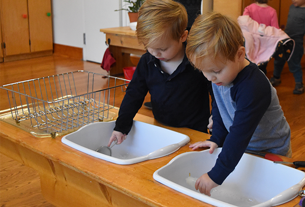 Montessori children are working in a kitchen sink.