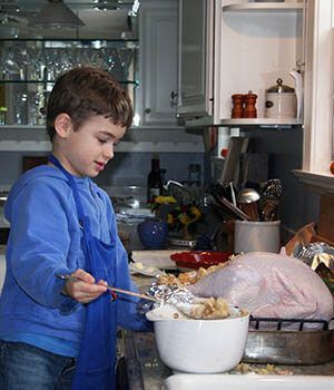 A young boy in a blue apron is preparing food in a kitchen