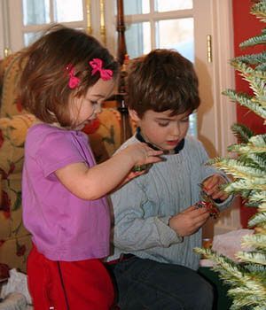 A boy and a girl are decorating a christmas tree together