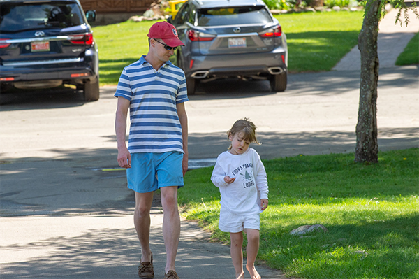 A parent and child walk together through a parking lot.