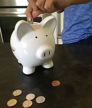 A person is putting a coin into a piggy bank.