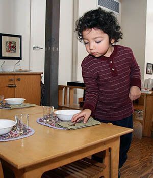 A young boy is setting a table his size