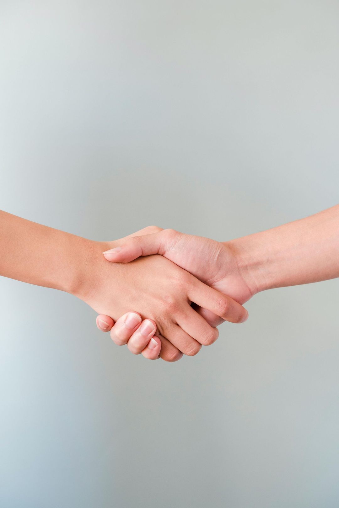 Two people are shaking hands on a gray background.