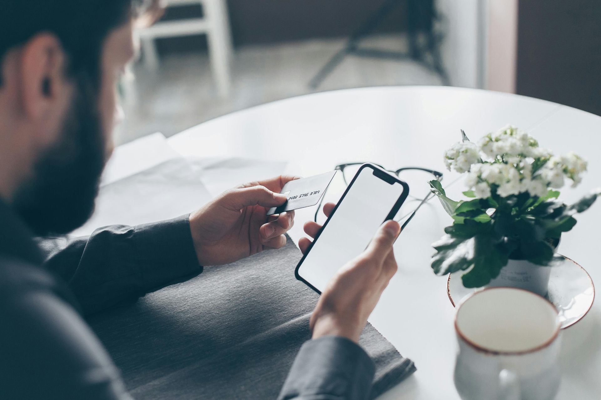 A man is sitting at a table using a cell phone.