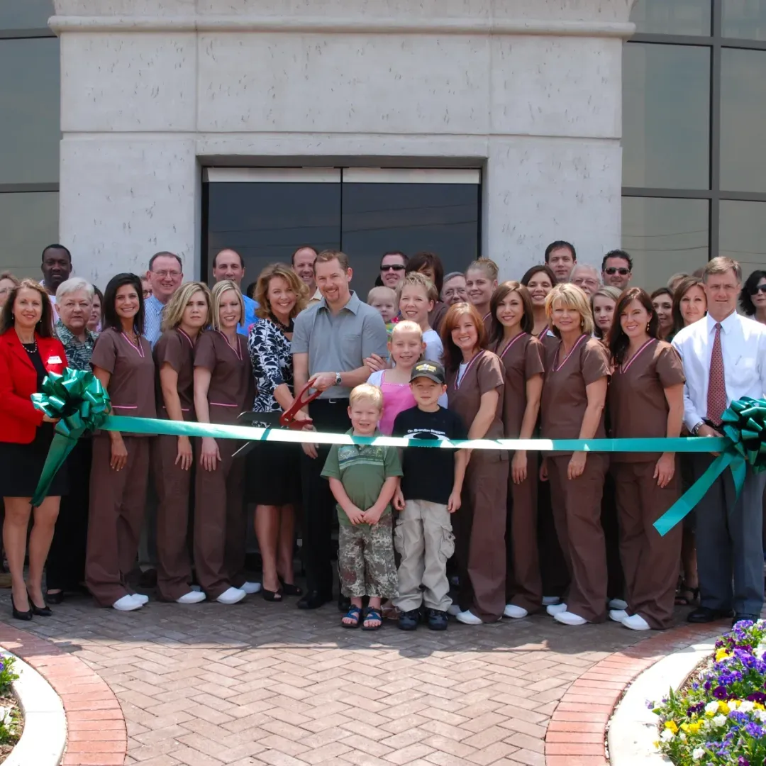 A group of people standing in front of a building with a green ribbon