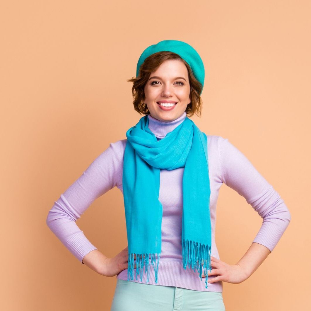 A woman wearing a green hat and a blue scarf