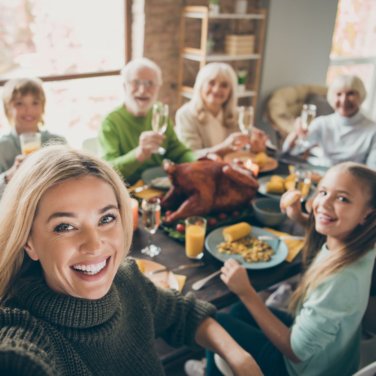 A woman is taking a selfie while sitting at a table with her family.