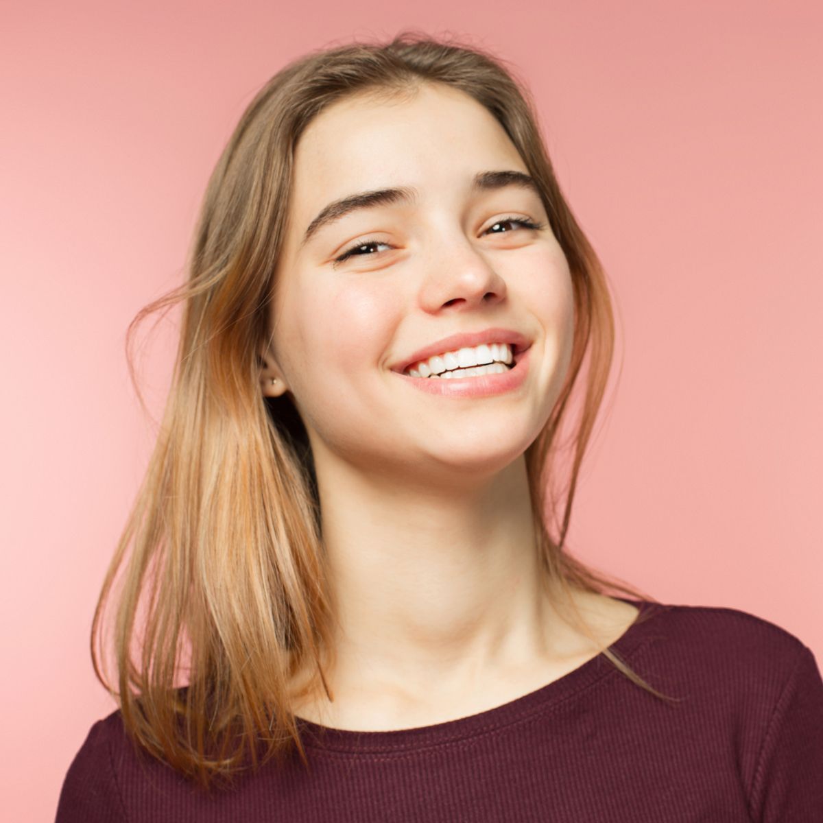 A young woman is smiling and wearing a purple shirt.