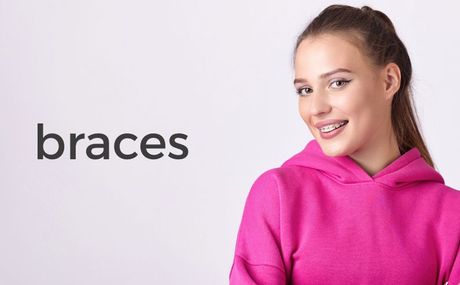 A young woman with braces on her teeth is wearing a pink hoodie.