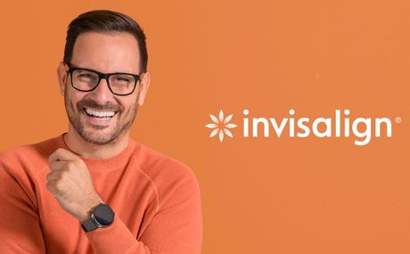 A man wearing glasses and a watch is smiling in front of an invisalign logo.