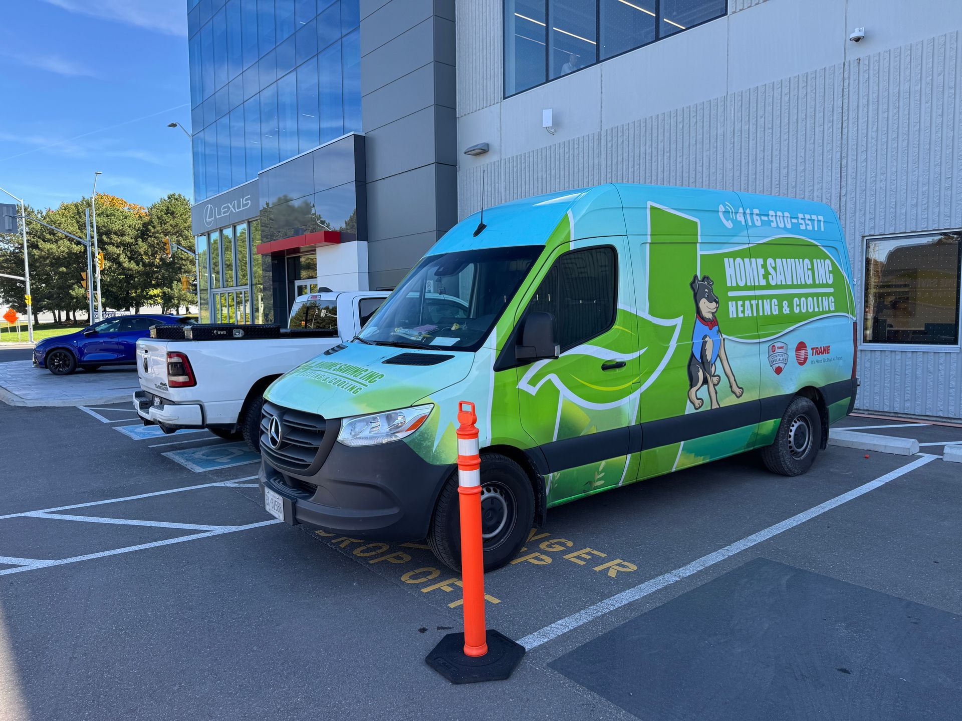 A green and blue van with logo parked in a marked parking space in front of a building.