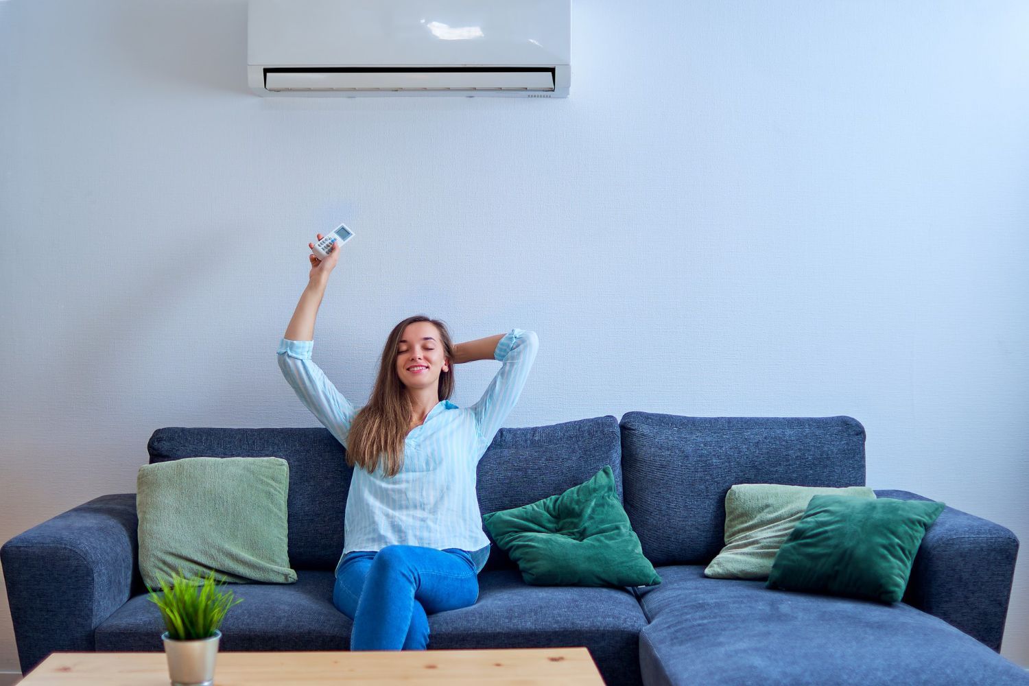 A woman is sitting on a couch in a living room holding a remote control.