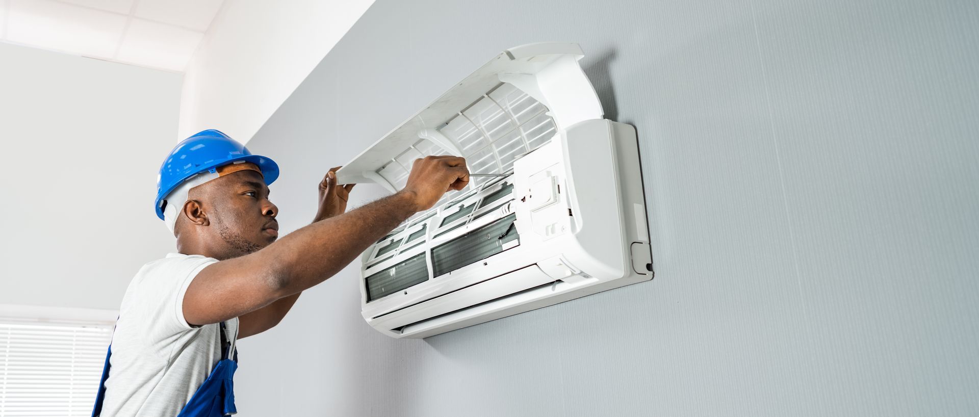 A man is installing an air conditioner on a wall.