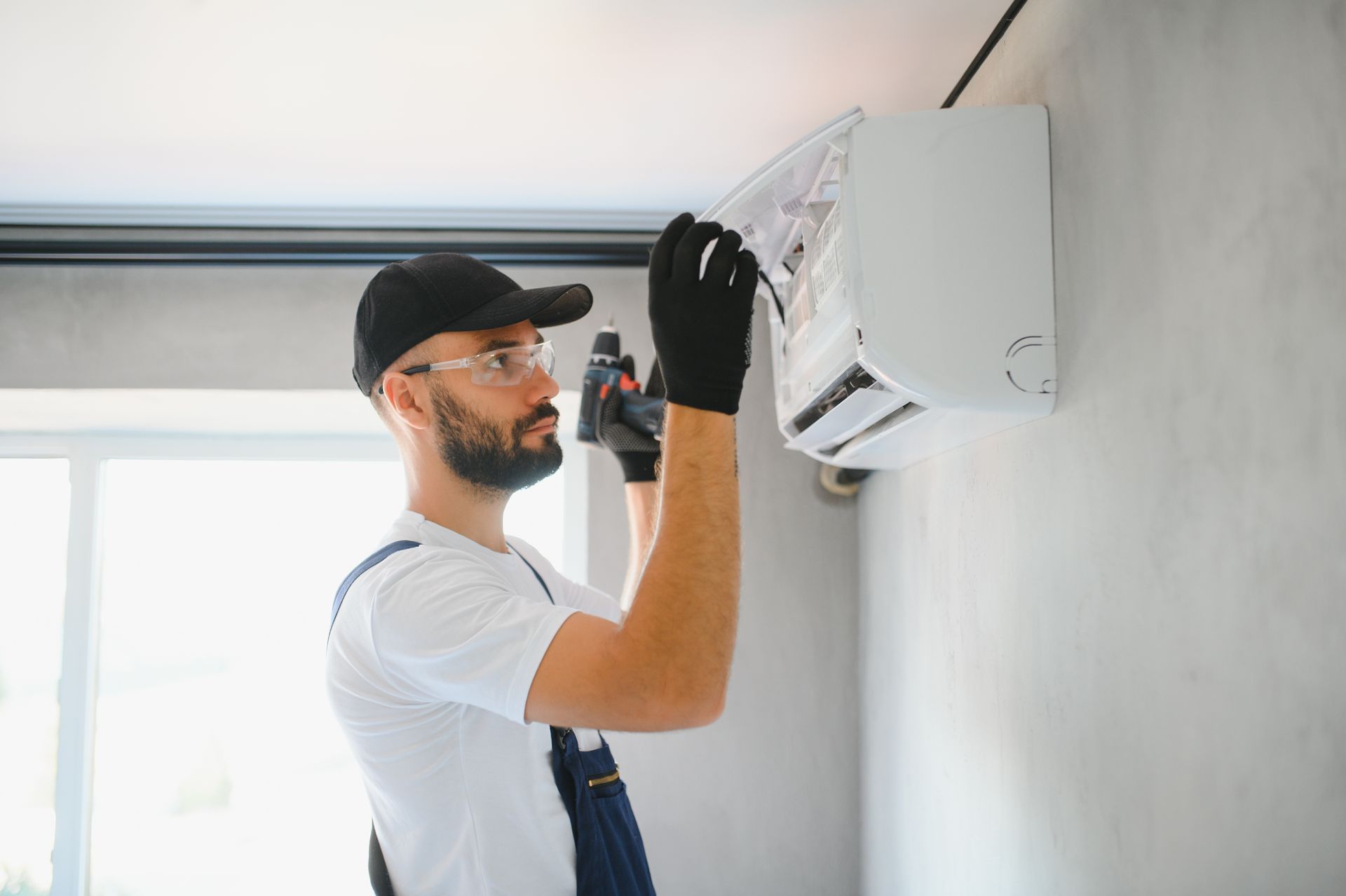 A man is installing an air conditioner on a wall.