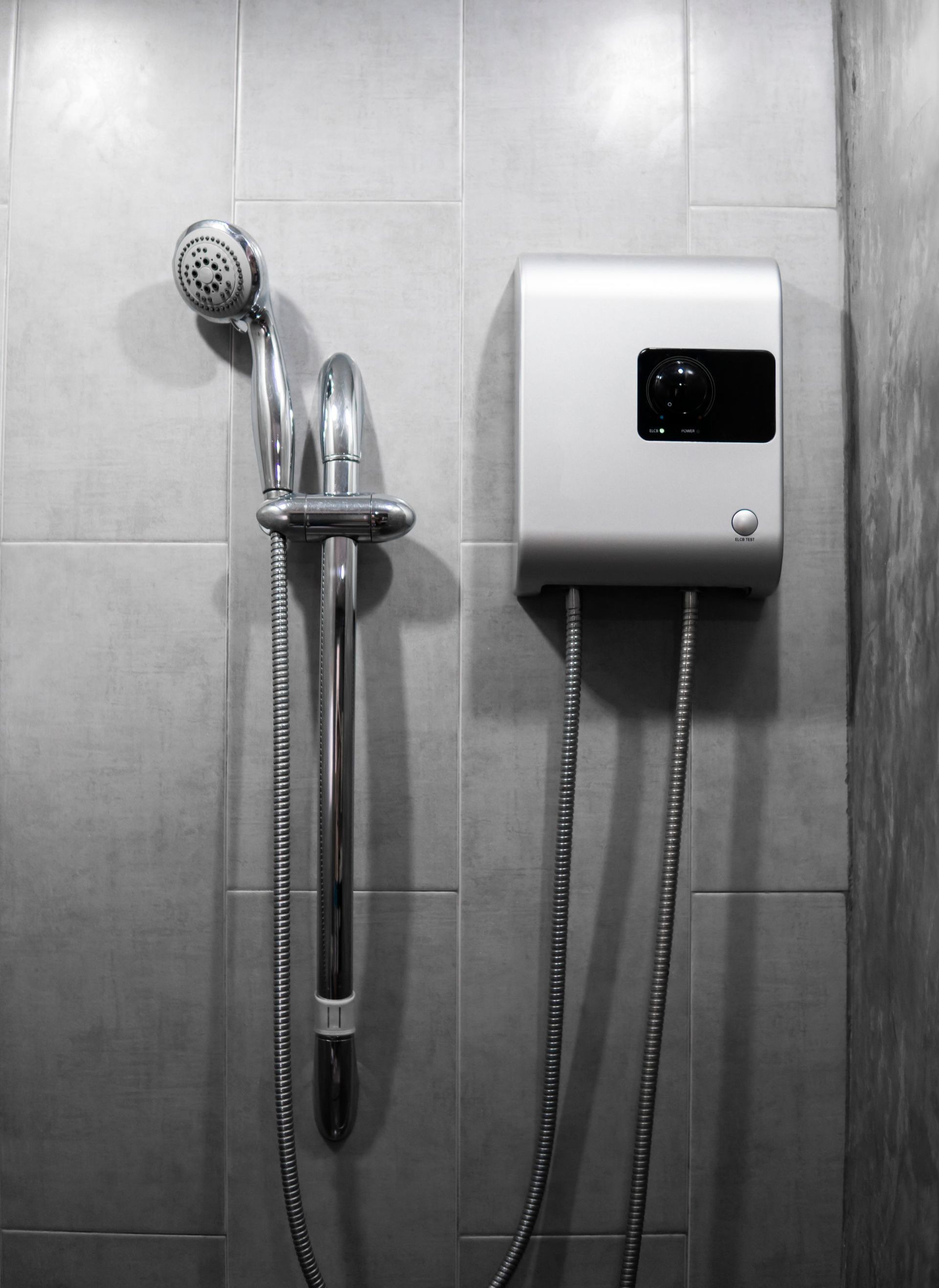 A black and white photo of a shower head and a water heater in a bathroom.