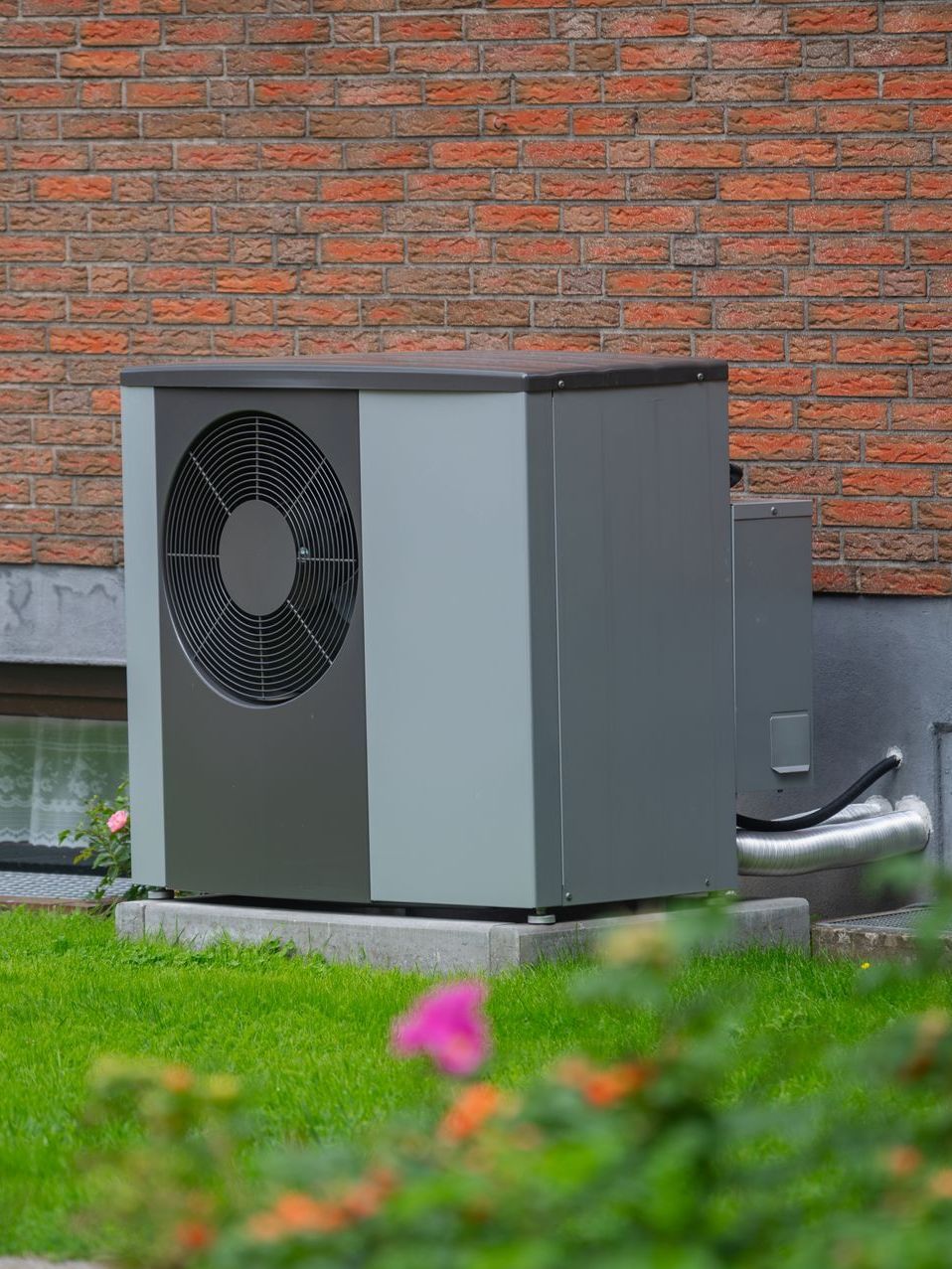 A white air conditioner is mounted on the side of a brick building