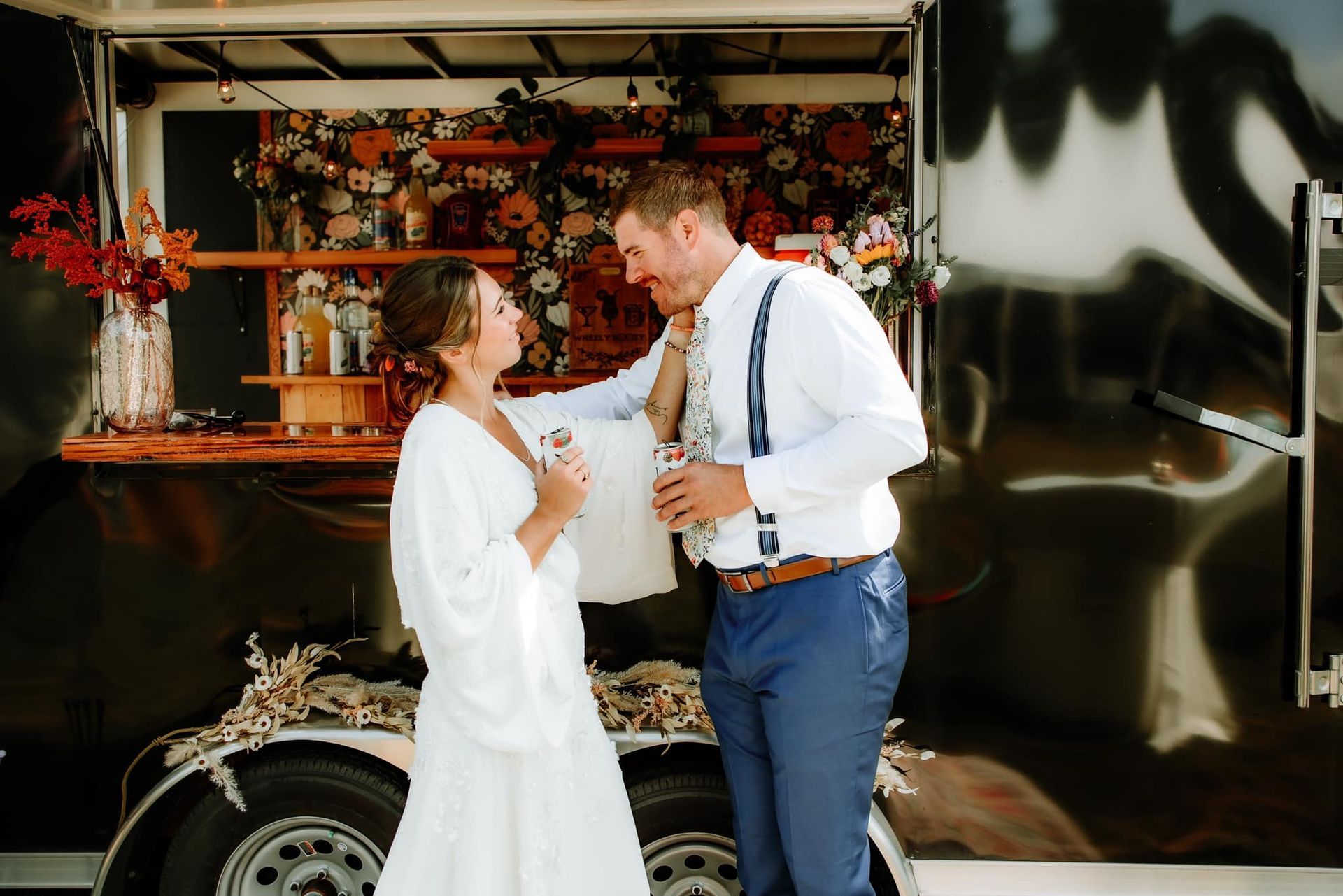 Bride and groom near a bar decorated with flowers. The couple is smiling and holding drinks.