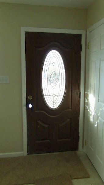 A brown door with a stained glass window in a hallway.