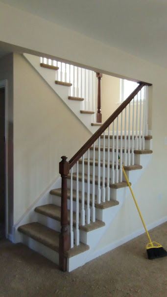 A staircase with white railings and a yellow broom