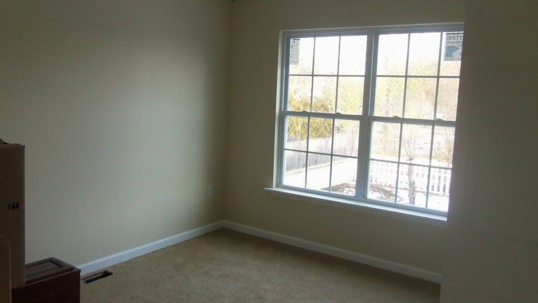 An empty room with a large window and a carpeted floor