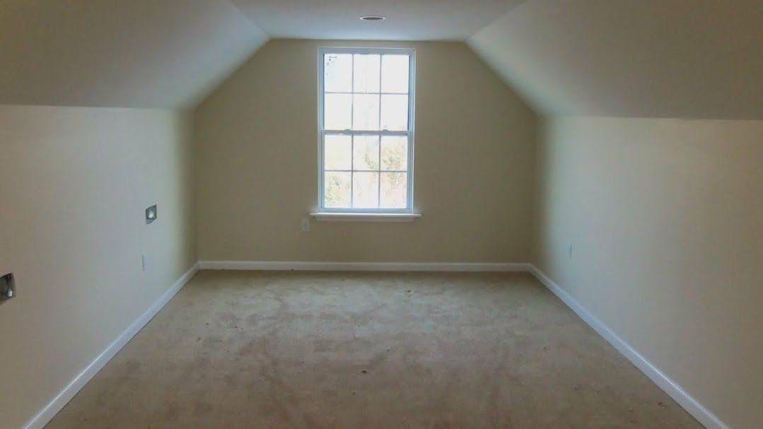 An empty room with a window and a vaulted ceiling.