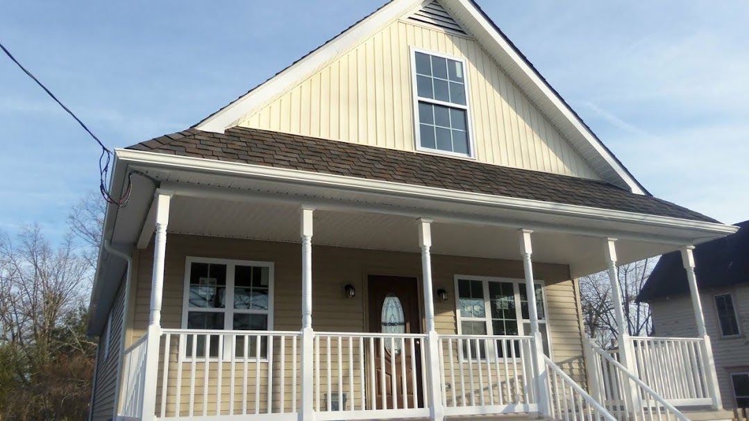 A yellow house with a porch and stairs