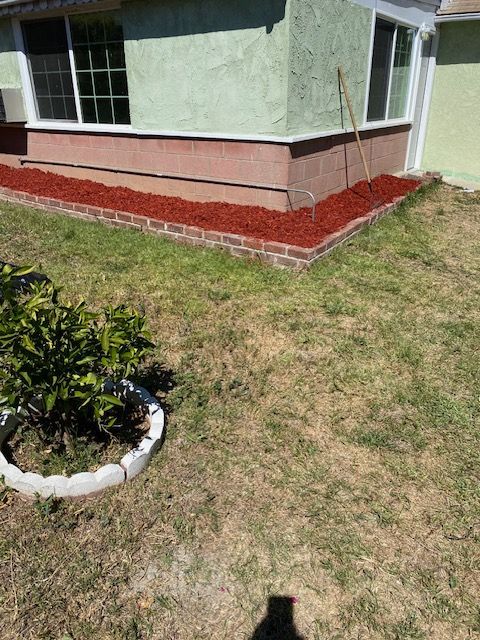 Green house corner with red mulch bed and brown lawn.