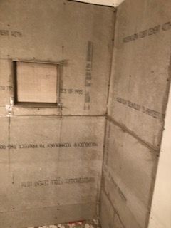 Gray cement board shower walls, including a small recessed area.