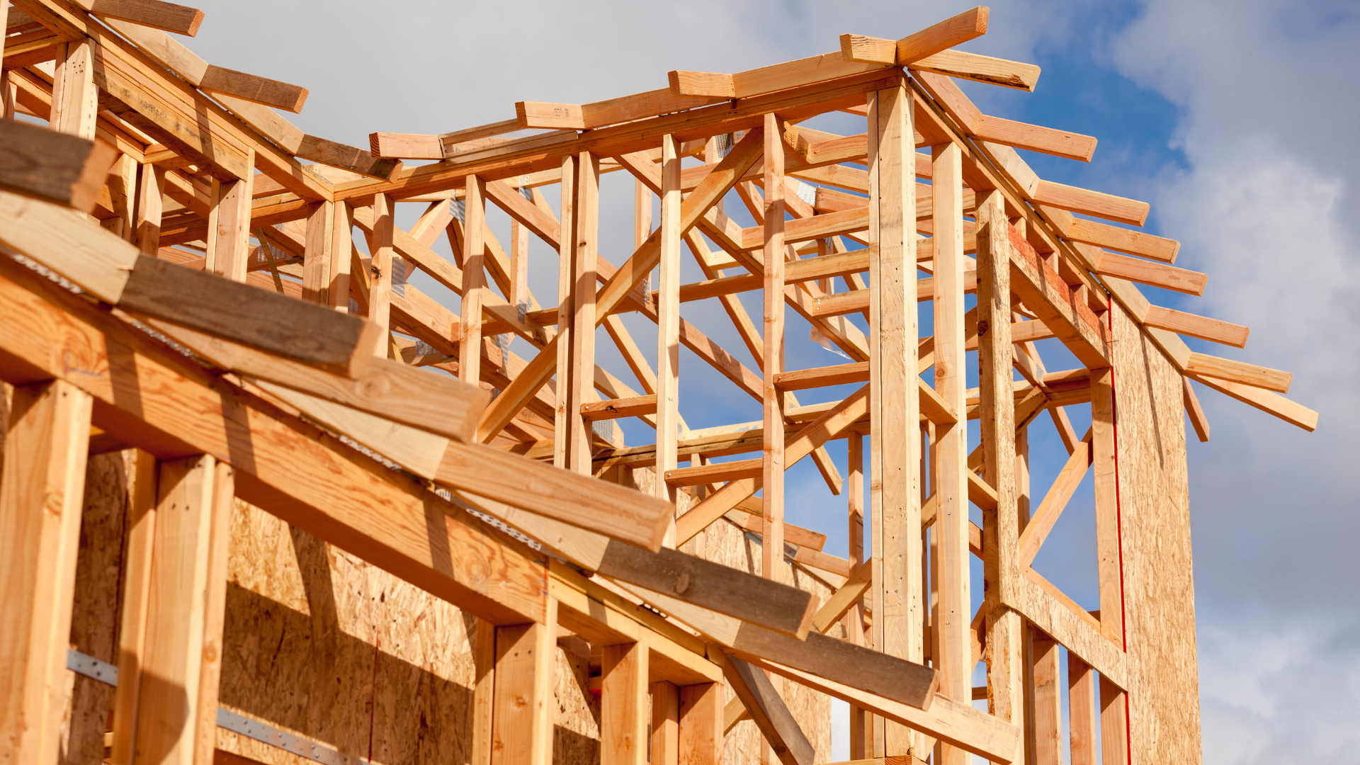 A wooden structure is being built with a blue sky in the background.