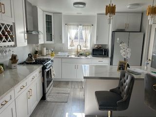 White kitchen with island, cabinets, appliances, and a bar stool.