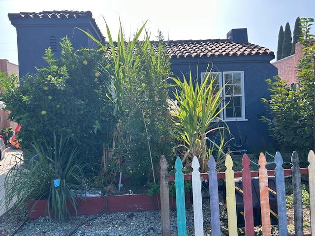 A wooden fence is along the sidewalk in front of a house.