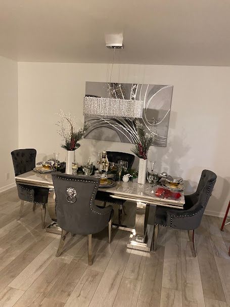 A dining room with a table and chairs and a painting on the wall.