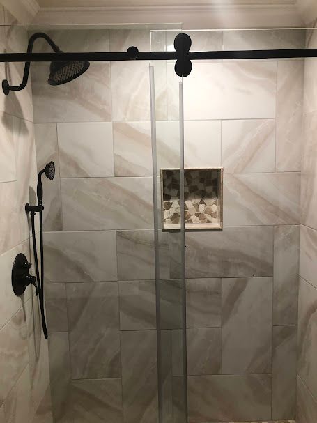 A shower with a sliding glass door and a shower head.