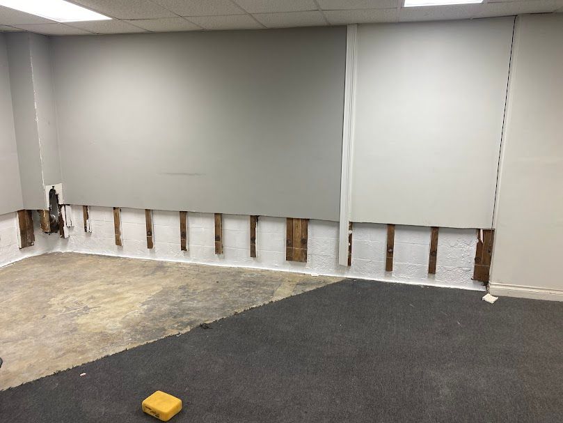 A room with a carpeted floor and a wall with a hole in it.