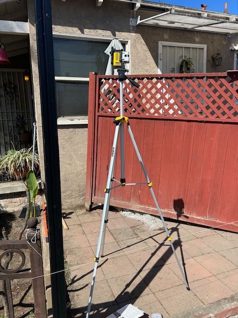 A tripod is sitting in front of a red fence