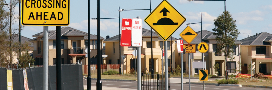 Road signs in front of suburban houses, including a bump sign.