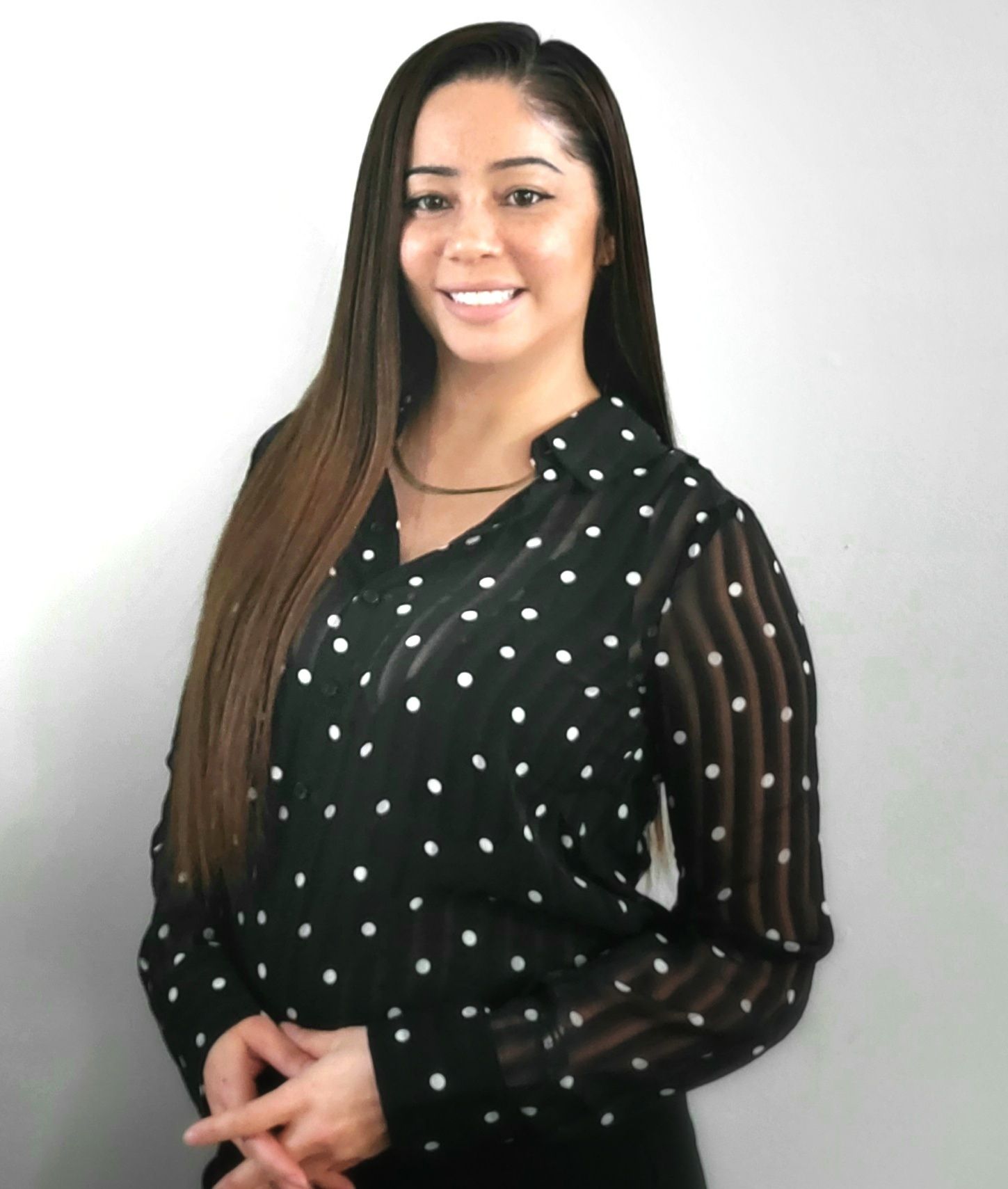 Woman smiling, wearing black blouse with white polka dots, standing in front of a white wall. Gloria Walton, Realtor