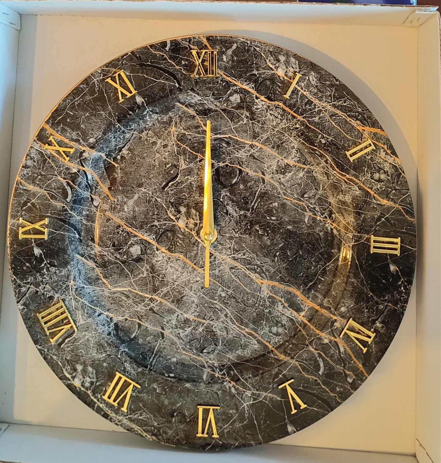 Un orologio nero e oro con numeri romani