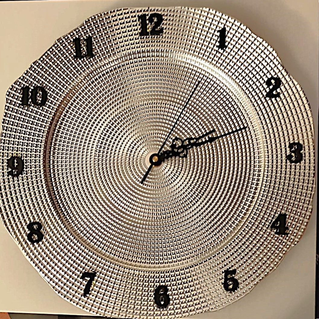 Un orologio d'argento con lancette nere su una superficie bianca